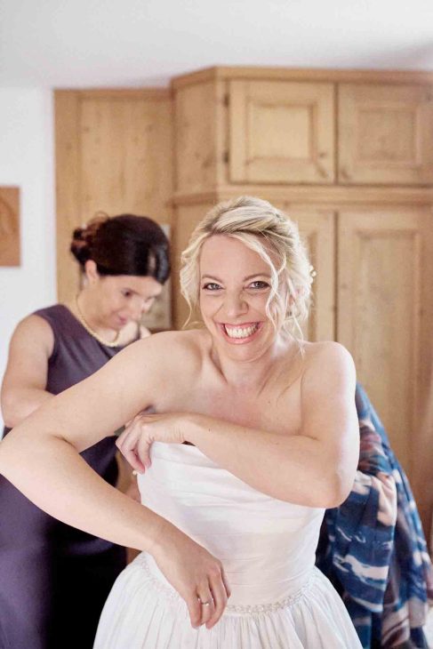 Primo piano della sposa bionda che sorride durante la preparazione del matrimonio in una casa in stile montano.