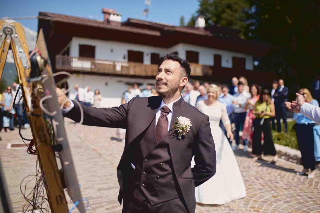 : Lo sposo Nicola in abito scuro attende la sposa all'altare della chiesa a Cortina.