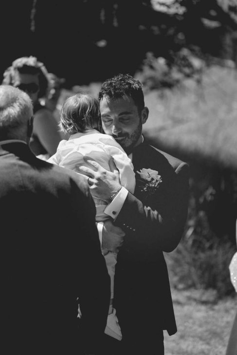 Abbraccio tra sposo e bambino in bianco e nero, scatto emozionale di un fotografo matrimonio Cortina d’Ampezzo.