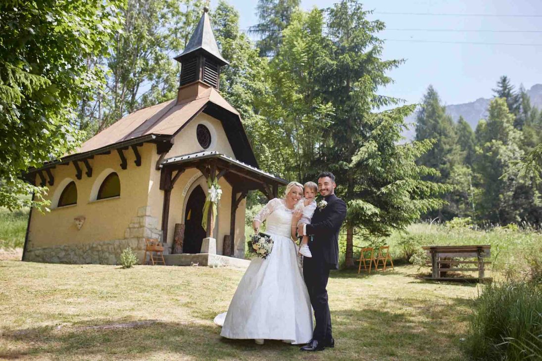 Ritratto di famiglia davanti a una chiesetta alpina curato da un fotografo matrimonio Cortina d’Ampezzo.