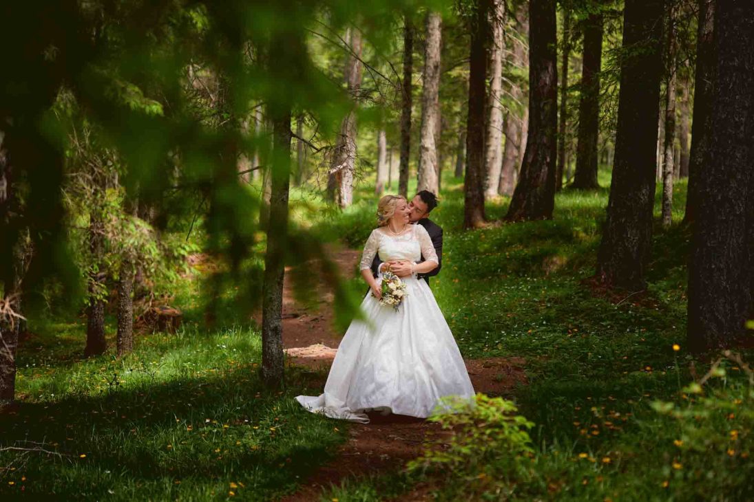 Sposi nel bosco durante un servizio curato da un fotografo matrimonio Cortina d’Ampezzo tra i pini e la luce soffusa.