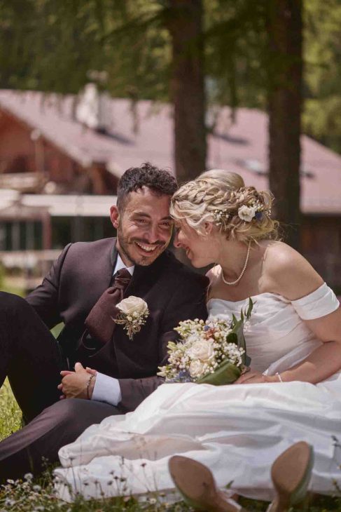 Primo piano degli sposi che sorridono vicini sul prato, ritratto intimo di un fotografo matrimonio Cortina d’Ampezzo.