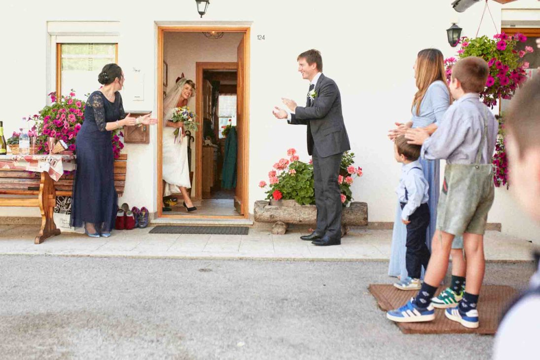 Uscita della sposa accolta da sposo e invitati ad Arabba, fotografo matrimonio Arabba Livinallongo.
