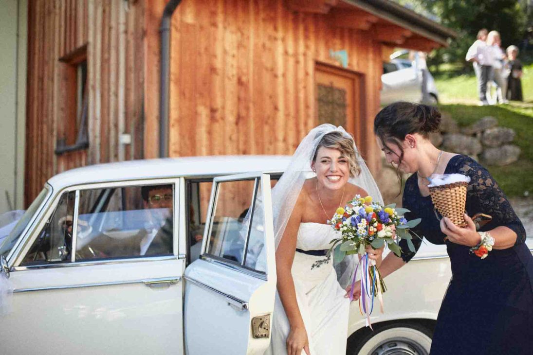 La sposa scende dall'auto d'epoca con la testimone a Cherz, fotografo matrimonio Arabba Livinallongo.