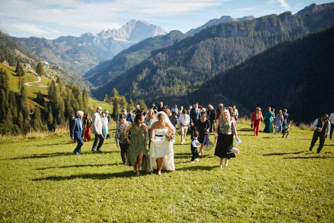 Sposi e invitati camminano in un prato alpino ad Arabba, servizio del fotografo matrimonio Arabba - dolomiti.