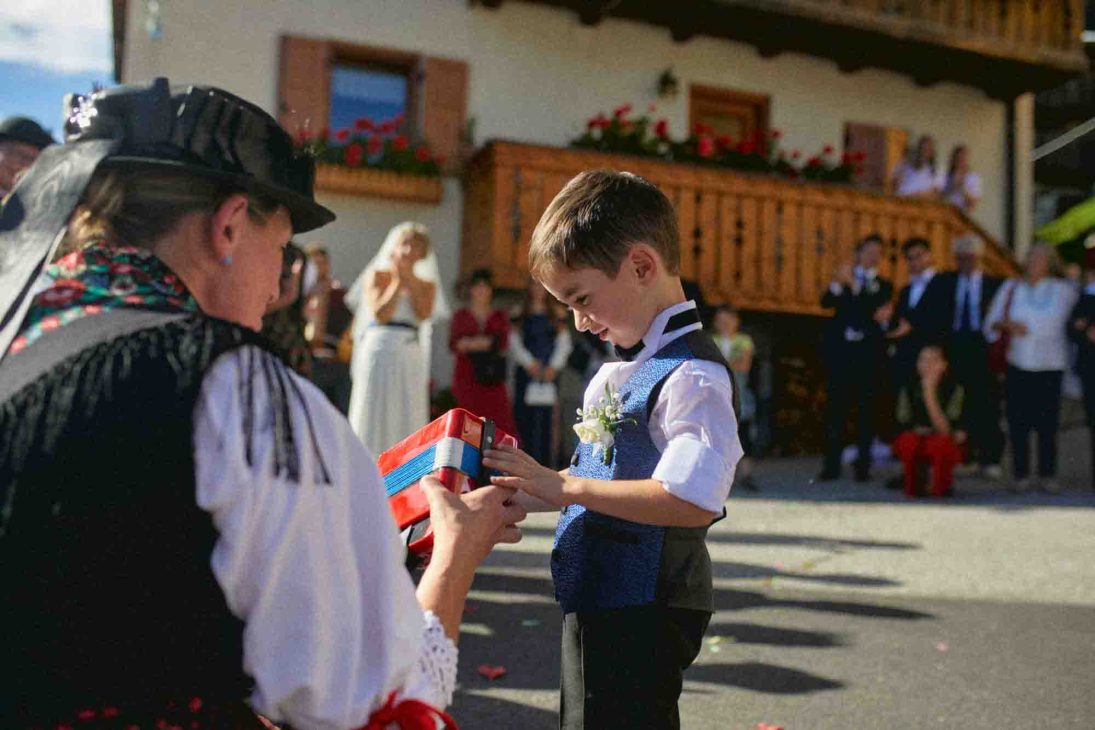 Bambino riceve una piccola fisarmonica rossa ad Arabba, servizio del fotografo matrimonio Arabba - dolomiti.
