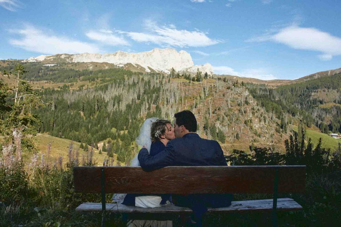 Sposi seduti su una panchina con vista sulle Dolomiti, servizio del fotografo matrimonio Arabba - dolomiti.