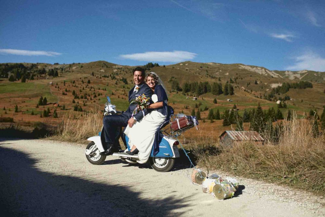 Sposi in Lambretta con barattoli nuziali tra i prati di Arabba, servizio fotografo matrimonio Arabba - dolomiti.