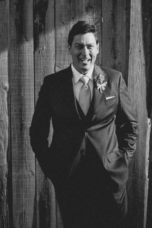 Ritratto sposo in bianco e nero davanti a un talvà in legno, servizio fotografo matrimonio Arabba - dolomiti.