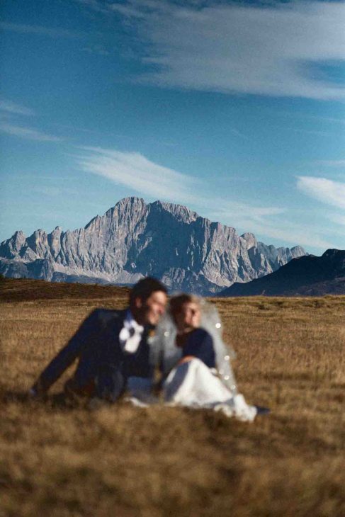 Sposi sfuocati in primo piano con vista nitida sul Monte Civetta, fotografo matrimonio Arabba - dolomiti.