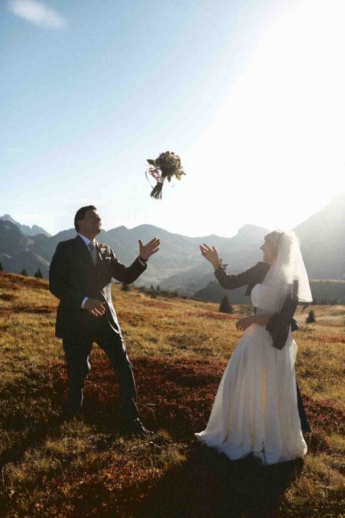 Lancio del bouquet degli sposi al tramonto tra le vette, servizio del fotografo matrimonio Arabba - dolomiti.
