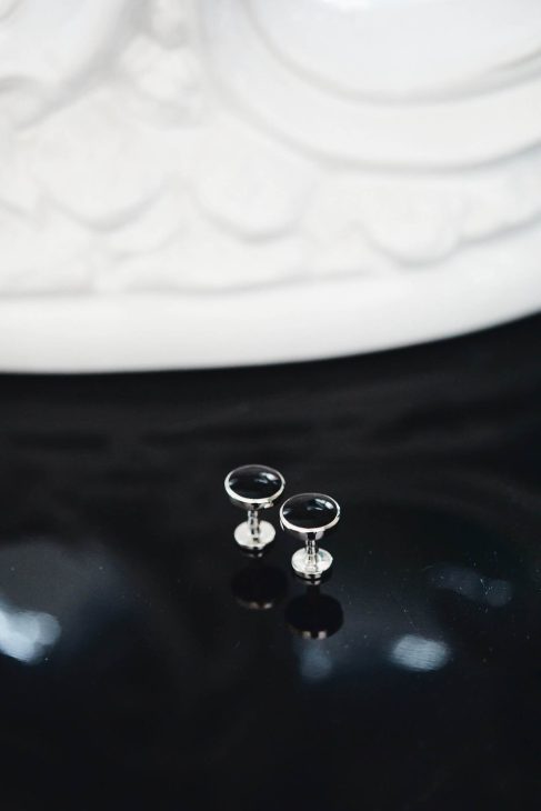 Fotografo matrimonio villa veneta Vicenza: dettaglio macro di gemelli da polso neri e argento su superficie lucida.