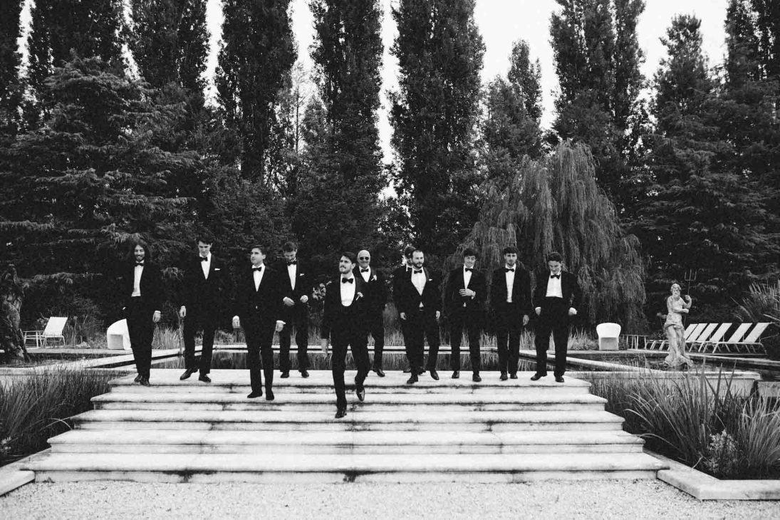 Fotografo matrimonio villa veneta Vicenza: sposo e testimoni in smoking scendono scalinata in pietra in un giardino storico.
