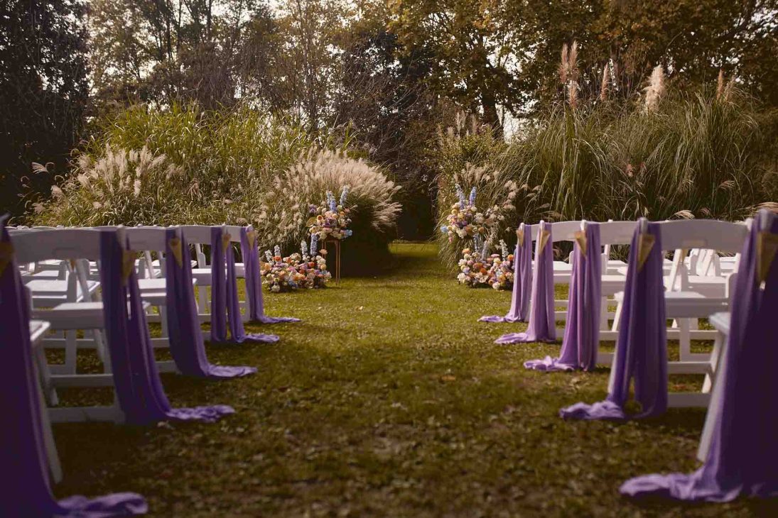 Fotografo matrimonio villa veneta Vicenza: allestimento cerimonia all'aperto con drappi lilla e composizioni floreali in giardino storico.