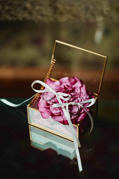 Dettaglio fedi nuziali su rosa antica in scrigno di vetro, scatto di un fotografo matrimonio villa veneta Vicenza.
