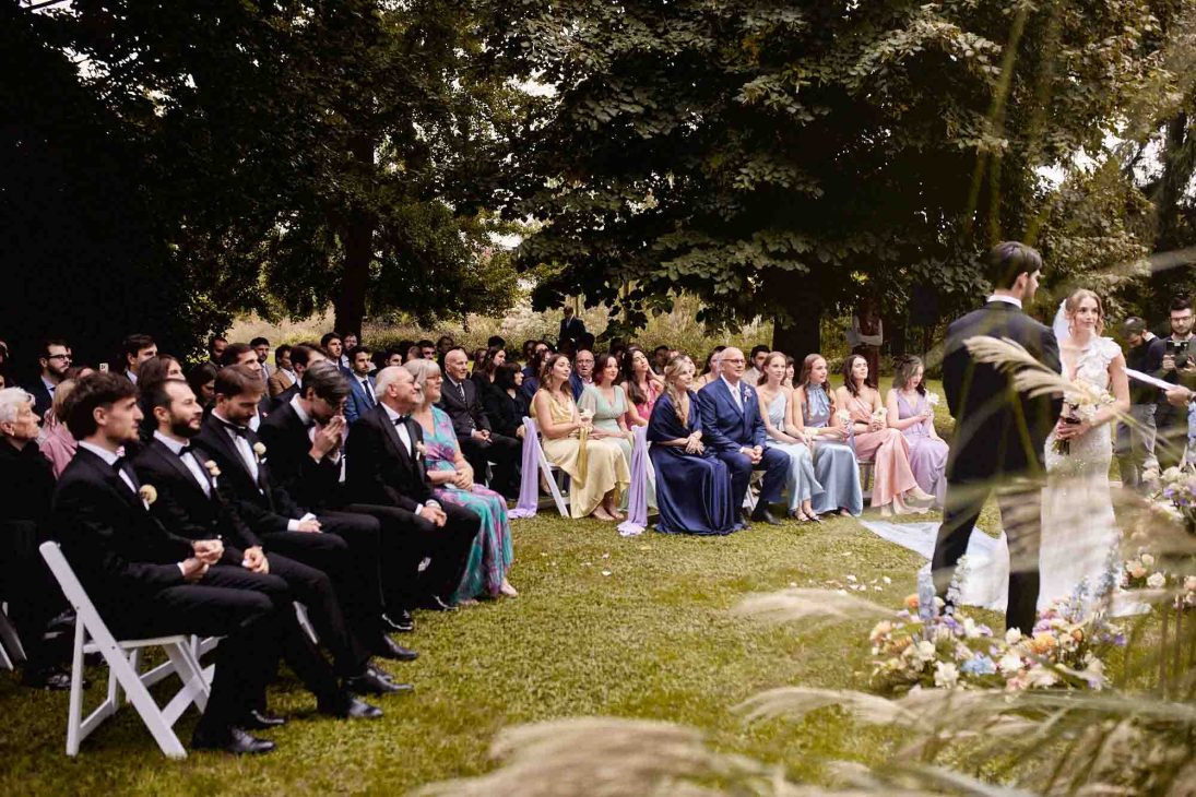 Cerimonia all'aperto con ospiti e genitori dello sposo nel parco per fotografo matrimonio villa veneta Vicenza.