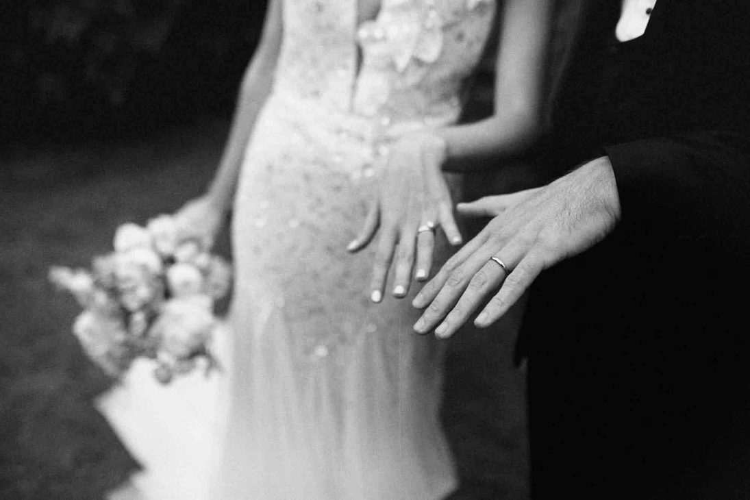 Dettaglio in bianco e nero delle mani degli sposi con fedi nuziali, scatto di fotografo matrimonio villa veneta Vicenza.