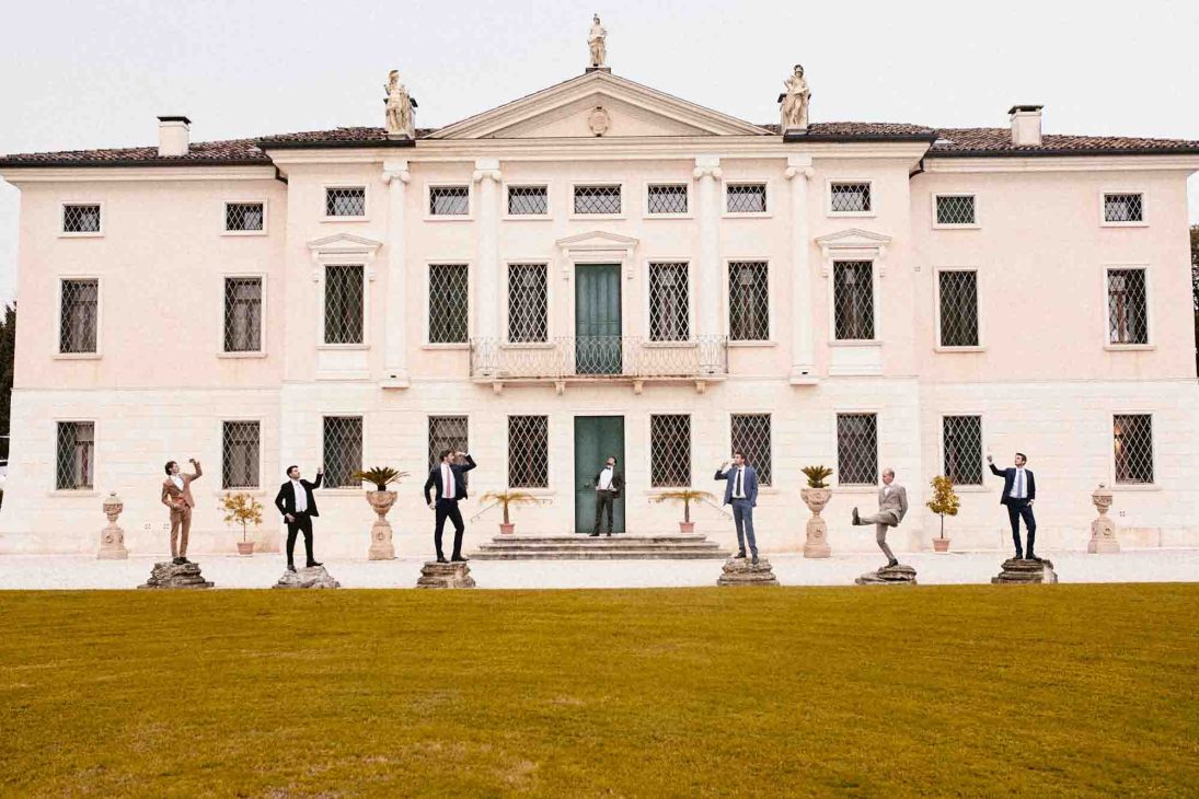 Gruppo di uomini posa elegantemente davanti alla facciata, scatto di fotografo matrimonio villa veneta Vicenza.