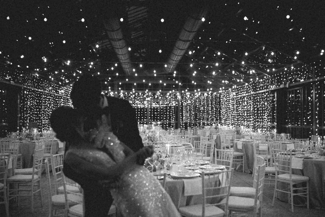 Sposi ballano abbracciati sotto un soffitto di luci a stringa in una serra, scatto di fotografo matrimonio villa veneta Vicenza.