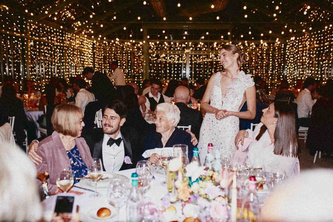 Sposi che interagiscono con gli invitati durante la cena in una serra. Fotografo matrimonio villa veneta Vicenza.
