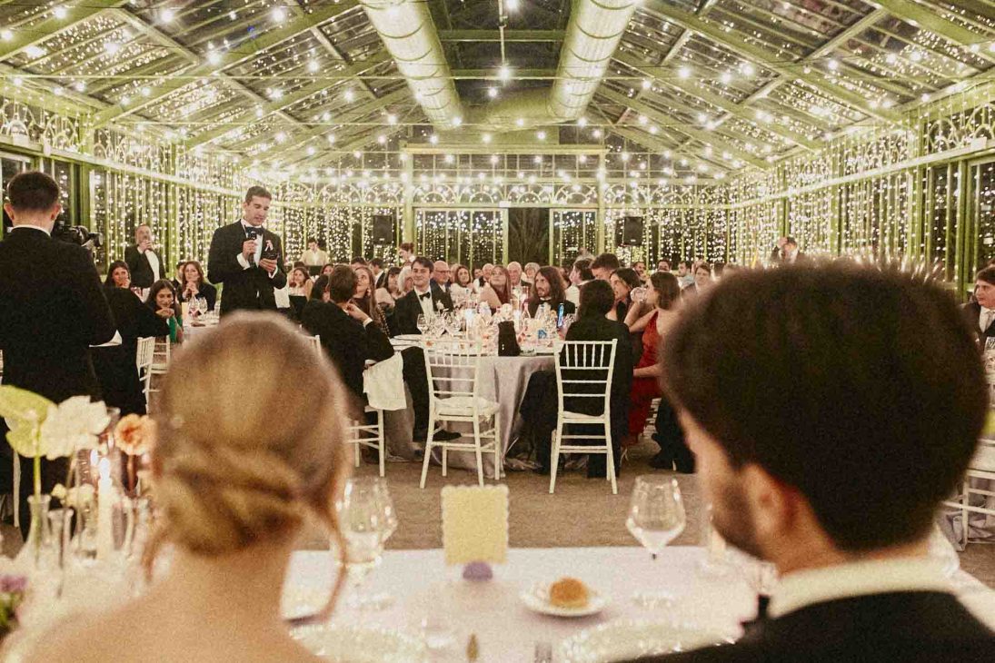 Discorso dello sposo durante il ricevimento serale illuminato in serra. Fotografo matrimonio villa veneta Vicenza.