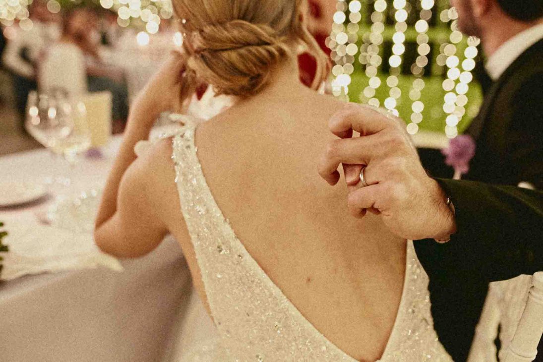Dettaglio della mano dello sposo sulla schiena della sposa durante una cena curata da un fotografo matrimonio villa veneta Vicenza.