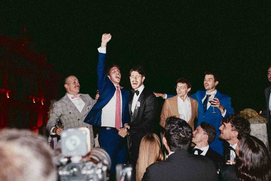 Sposo festeggia con gli amici durante il party serale all'aperto. Fotografo matrimonio villa veneta Vicenza.